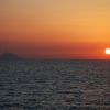 Tramonto rosso su mare calmo.