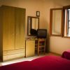 Camera con letto, armadio, scrivania, sedia e TV. Finestre aperte.