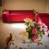 Due letti singoli con copriletti rossi e tavolo con fiori.