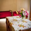 Tavolo con tovaglia floreale e fiori, due letti sullo sfondo.
