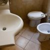 Lavandino bianco, WC e bidet su pavimento piastrellato.