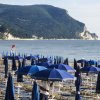 Spiaggia con ombrelloni blu e mare.