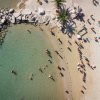 Spiaggia con ombrelloni arancioni e persone in acqua.