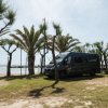 Camper parcheggiato tra palme vicino alla spiaggia.