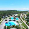 Villaggio turistico con piscine e bungalow, circondato da natura.
