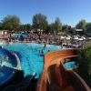 Piscina affollata con scivoli e ombrelloni.