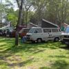 Furgoni e camper parcheggiati in un'area verde boschiva.