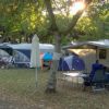 Camper con veranda sotto alberi in un campeggio.