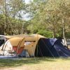Tenda da campeggio tra alberi e auto parcheggiate.