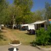 Area campeggio con camper e tende tra gli alberi.