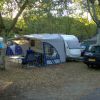 Camper e auto parcheggiati sotto gli alberi al campeggio.