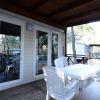 Veranda esterna con tavolo e sedie bianche.