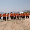 Gruppo di persone in tuta arancione corre sulla spiaggia vicino al mare.