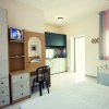Camera da letto con mobili semplici e TV accesa.