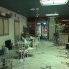 Interno di una caffetteria con sedie bianche e frigoriferi.