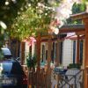 Una fila di case mobili con veranda e un'auto parcheggiata, circondate da vegetazione e fiori.