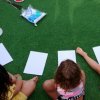 Bambini seduti sull'erba con fogli bianchi per dipingere.