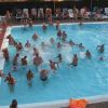 Persone che giocano in una piscina affollata circondata da lettini.