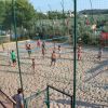 Persone giocano a beach volley su un campo sabbioso all'aperto.