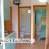 Cucina e due ingressi. A destra, una stanza con letto e a sinistra, un bagno.
