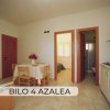 Soggiorno con tavolo e sedie, cucina a destra e due ingressi.