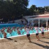 Una piscina piena di persone in acqua mentre istruttori animano un'attività sul bordo.