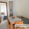 Sala da pranzo con tavolo, sedie e letto singolo. Porta aperta su una camera con letto.