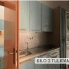 Angolo cottura con mobili blu e porta aperta verso un balcone.