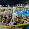 Vista dall'alto di persone che socializzano vicino a una piscina con bandierine colorate appese.