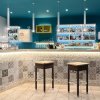 Bancone bar moderno con sgabelli e luci soffuse.