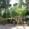Parco giochi con altalena tra alberi alti.