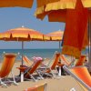 Spiaggia con ombrelloni e lettini arancioni.