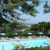 Piscina con sdraio, alberi e vista mare.