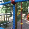 Parco giochi con strutture colorate e alberi intorno.