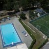Piscina accanto a campo da calcio con sedie a sdraio.