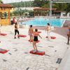 Persone fanno esercizi davanti a una piscina all'aperto. Pavimento in pietra.