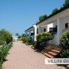 Villette bianche con vialetto in mattoni e cespugli fioriti ai lati.