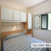 Camera da letto con letto matrimoniale e armadietti sopra, finestra aperta sulla destra.