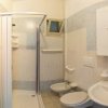 Bagno con doccia, bidet, lavandino e specchio, piastrelle chiare e accenti blu.
