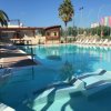 Piscina con bordo a sfioro, lettini prendisole e ombrelloni colorati sullo sfondo.
