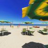 Spiaggia con ombrelloni verdi e gialli, lettini e un mare calmo all'orizzonte.