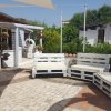Area relax con divani di pallet e vegetazione.