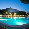 Piscina illuminata di sera con edificio sullo sfondo.