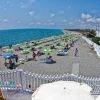 Spiaggia con ombrelloni verdi e gialli sul mare.