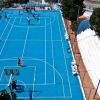 Partita di basket su un campo blu con spettatori seduti.