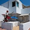 Casa bianca con veranda, ombrellone blu e piante.