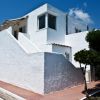 Casa bianca con scale esterne e cielo blu.