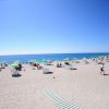 Spiaggia con ombrelloni verdi e cielo azzurro.