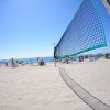 Rete da beach volley su spiaggia con ombrelloni.