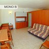 Monolocale con divano, angolo cottura e tavolo.